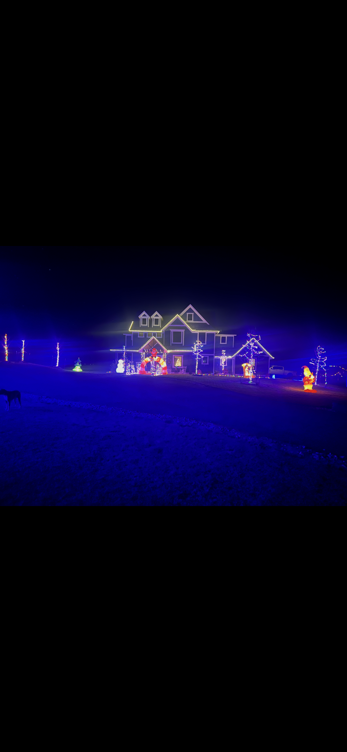 Colorful holiday lighting display across a residential property at night